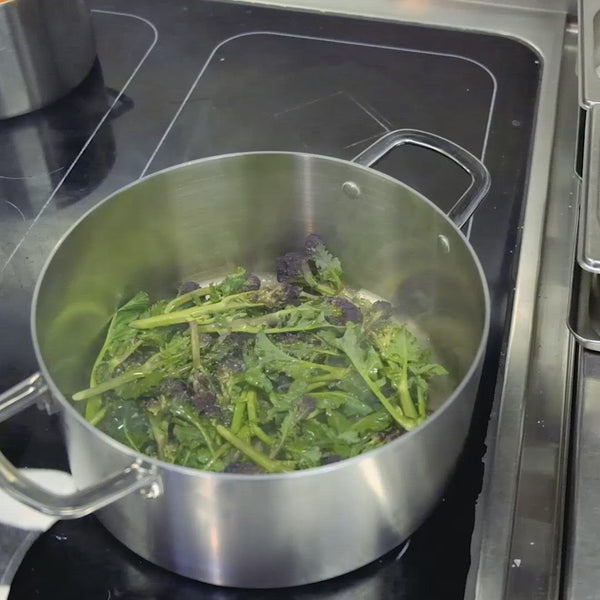 Short video of purple sprouted broccoli being cooked in a stainless steel pan